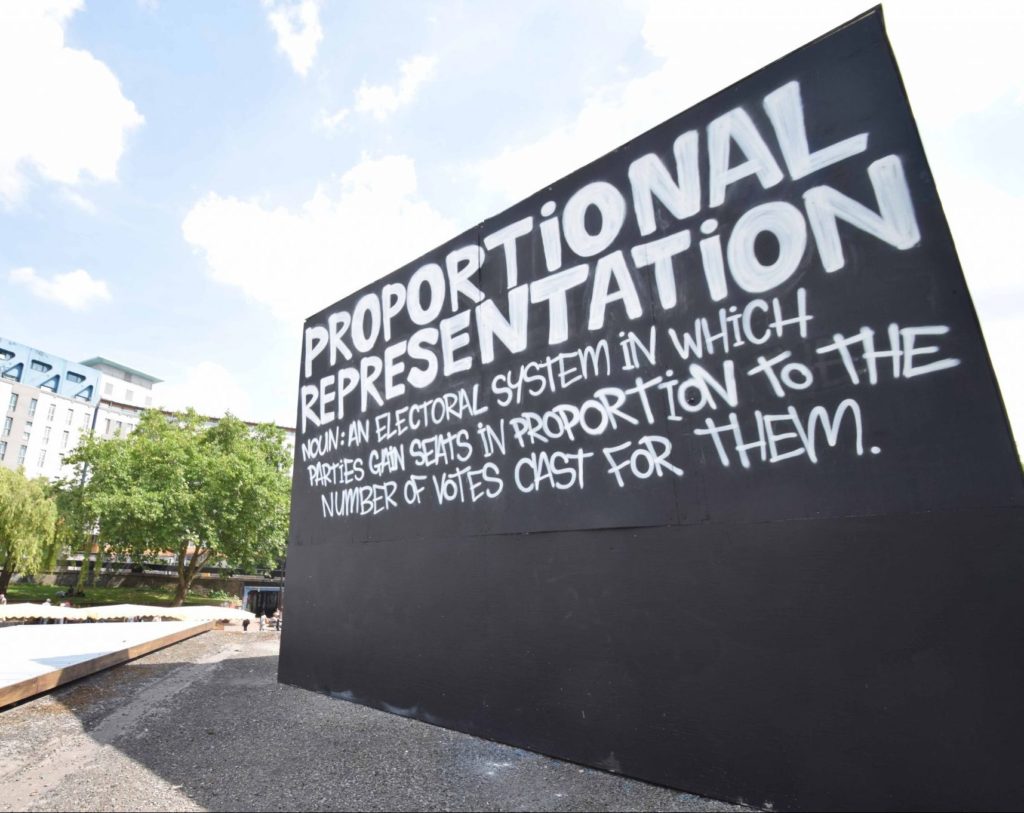 Call for democracy: electoral reform But not only the car-crash direction of the Tories needs to be addressed. Our current electoral system is fraught with inconsistencies and problems. You can only vote for one person per party. If you don’t like this person, you have to either vote for them anyway, or vote for another party; Tactical voting is useful to keep a party out, but it doesn’t necessarily reflect what you want and believe in. Without tactical voting, smaller parties would have done much better in Bristol and elsewhere; Seats in Parliament don’t match how we vote, because it doesn’t take into account the overall number of votes. In 2015 the Scottish SNP won just under half of the votes, but got 95% of the seats. For the 2017 election, this is particularly striking when you look at the votes compared to the seats from the DUP and the Green Party. With a total of 292,316 votes, the DUP gained 10 seats in Parliament, and got invited to govern alongside the Conservatives. Compare that to the Green Party, who gained a total of 525,435 votes and has one single seat in Parliament. This is so far off what people vote for and the reason is firmly rooted in the current ‘first past the post’ system, which allows a small party like the DUP to rise to power. This voting system means that we get governments we didn’t vote for. Our voting system urgently needs to be addressed if we want to call this democracy. Because everyone deserves to be heard, and this issue needs awareness. Check out the Electoral Reform Society for information, petitions and campaigns. Meanwhile our Cube on the Bearpit (photos below) raises these issues for passers-by. Go and have a look, and enjoy the sun!